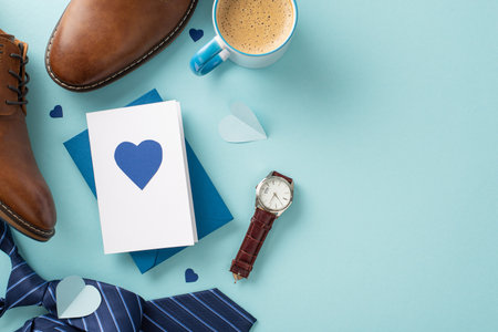 Modern Father's Day idea. Top-down view of envelope with postcard, necktie, leather shoes, wristwatch, accessories, and coffee cup on a pastel blue background with a blank spaceの写真素材