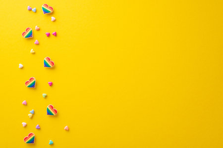 Display your support for the LGBT community with this top view flat lay of parade symbolic accessories on yellow backdrop, featuring rainbow color pin badges, hearts, with a blank space for text or adの写真素材