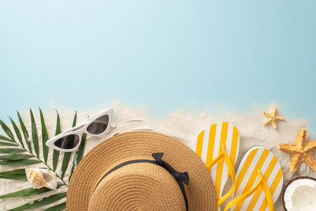 Summer beach holiday idea. Top view of vacation essentials: sunhat, flip-flops, shell, starfish, palm leaves, coconut. Empty space for text or ad on sandy and water backdropの写真素材