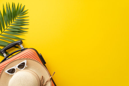 Summer retreat inspiration. Top view composition featuring a suitcase, beach gear, sunglasses, sunhat, and green palm leaf against a striking yellow backdrop. Perfect for text or promotional contentの写真素材