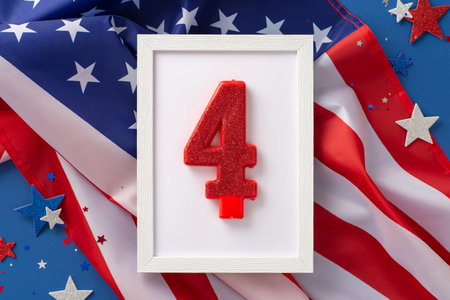 US Independence Day concept. Top view photo of wooden frame with the number 4 surrounded by blue, white and red glitter stars and american flag on blue isolated backgroundの写真素材