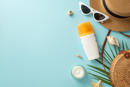 Prepare for a day in the sun with these essentials on a pastel blue background. Top view of unmarked...