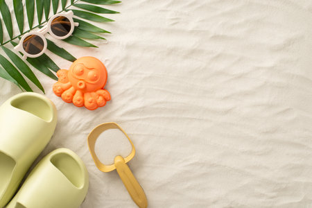 Discover the joy of a summer getaway with children by the sea: Above view picture featuring sand toys for children, palm leaf, sunglasses and slippers on isolated sandy background with copyspaceの写真素材