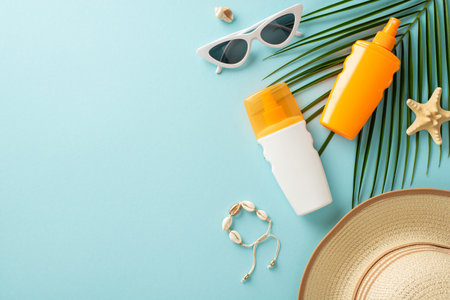 Top view of sun protection items on pastel blue backdrop: label-free sunblock cream bottles, sunglasses, stylish hat seashell bracelet, starfish, and tropical palm leaf. Perfect for adding text or adの写真素材