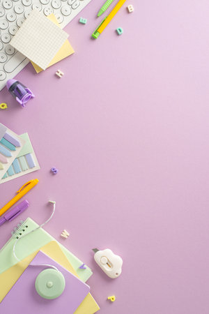 Step into the world of distant studying from home with this captivating top-down vertical view, presenting keyboard, planner and office supplies on pastel purple background. Room for text or advertisementの写真素材