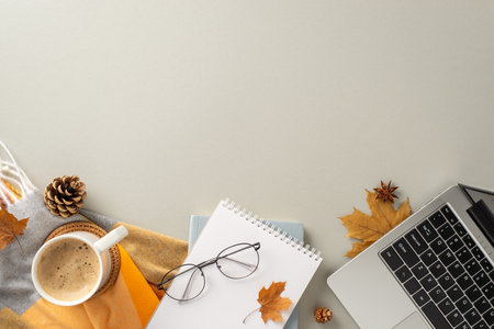 Coziness of working from home with laptop concept. Above view photo of empty notepad, laptop, cozy blanket, pinecones and spices, glasses and laptop on isolated gray background offering copy-spaceの写真素材