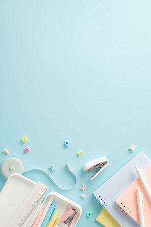 Enhance your academic success with captivating top vertical view showcasing wide range of stationery and alphabet letters on blue isolated background. Utilize empty circle for text or advertisementsの写真素材
