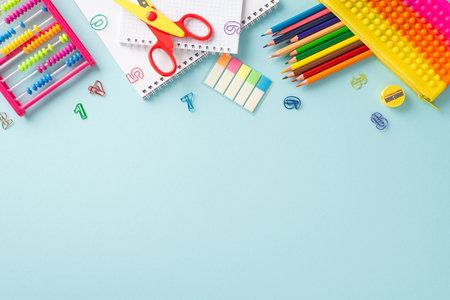 Explore the wonders of education for young learners: top view photo showcasing an assortment of vibrant school supplies on a pastel blue isolated background, with copyspace for text or promotionsの写真素材