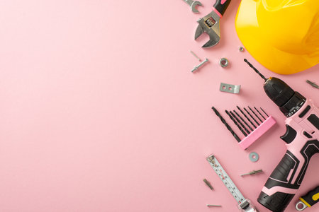 Embracing the significance of women's contributions on Labor Day. Overhead image showcasing a yellow helmet and construction tools on a pink isolated background, with copy-space for text or adsの写真素材