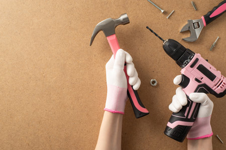 Honoring female builders' skills. Top view photo featuring a woman's hand holding construction tools and other instruments on plywood background, providing space for text or advertising contentの写真素材