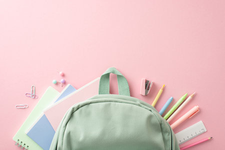Embrace the back-to-school excitement. Top view of stationery arranged in form of fan on pastel pink, alongside a sage rucksack. Advertise your message nowの写真素材