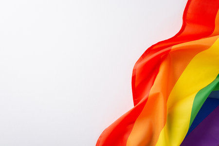 Symbolizing unity and progress: This top view photo showcases a rainbow flag on a white canvas empty...