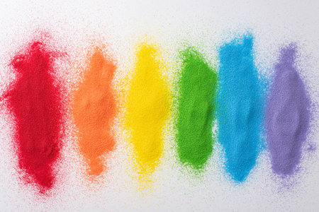 Vibrant sand flag, top view, honors LGBT history month. Colorful sand forms a rainbow flag on white backdrop, offering an open space for supportive messagesの写真素材