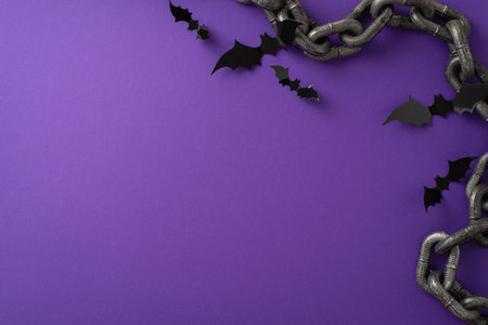 Spooky Halloween gathering concept. Bird's-eye top view picture highlighting black paper bats Halloween-themed chains on a purple isolated background with ample copyspace for text or advertisingの写真素材