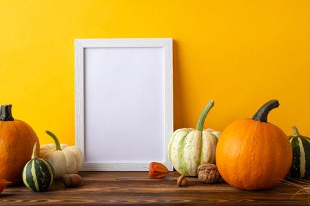 Thanksgiving Crop Exhibition. Side view picture showcasing empty photo frame and abundant harvest arrangement on rustic wooden table, set against orange wall background, with space for text or advertの写真素材