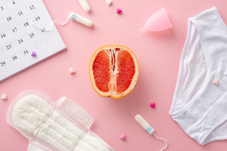 Top view of feminine hygiene products: pads, tampons, menstrual cup, and underwear, alongside a...