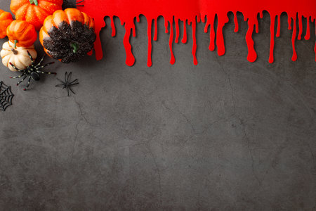 Set up spine-chilling vibes. Overhead view of Halloween elements - pumpkins, eerie spiders, cobweb, blood traces on textured backdrop. Blank room for text or advertisingの写真素材