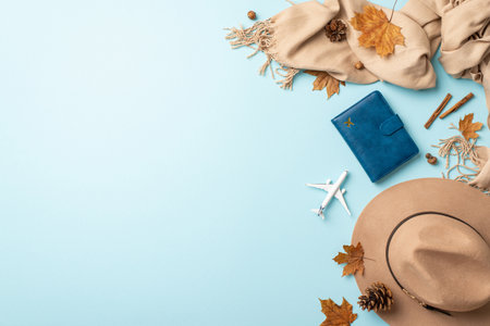 Elevate your autumn escape. Top view image featuring passport, plane miniature, plush cashmere scarf, trendy felt hat against soothing light blue isolated backdrop, inviting your text or advertisingの写真素材