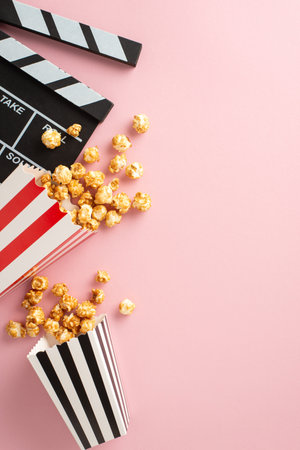 Cinematic Treats: vertical top view shot of popcorn, and a clapperboard on pastel pink, setting the stage for a delightful movie night with friendsの写真素材