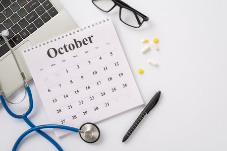 Telemedicine consultation idea. Top view of laptop, stethoscope, October calendar, glasses, pen, and pills on white background with text or ad spaceの写真素材