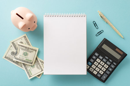 Surge in pricing and utility outlines idea. Top view snapshot of piggy bank, dollars, calculator, memo pad, pen, clips on pale blue setting with space for text or adの写真素材