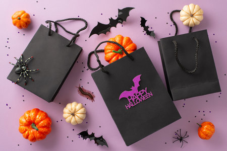 Sharing festive spirit by gifting for Halloween. An overhead shot exhibits a black paper gift bag, adorned with Halloween decor, against purple isolated backdropâexcellent for ads or accompanying textの写真素材