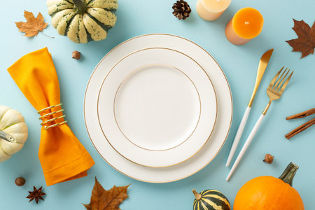 Captured from above, an autumnal-themed Thanksgiving family feast is portrayed. Gilded plates, rustic cutlery, and fall decorations rest on light blue backdrop, offering space for text or ads.の写真素材