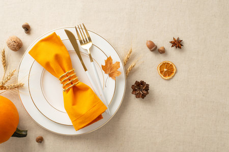 Thanksgiving family reunion amidst autumn season. Top view photo of golden plates, vintage cutlery, and fall-themed ornaments rest on a beige tablecloth isolated backdrop, perfect for text or advertsの写真素材