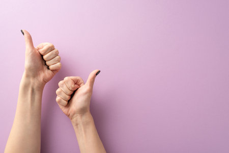First person top view of young girl's hands, her elegant black manicured fingers forming thumbs-up gestures. Set against lilac backdrop, leaving room for text or promo. Delightful expressions capturedの写真素材