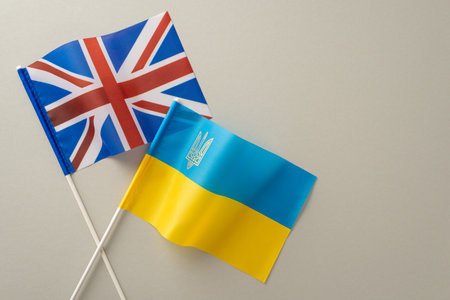Capture the essence of Ukraine's global alliances with a top view image of Ukrainian and UK flags against a muted gray backdrop. Ample space for your message or advertisementの写真素材
