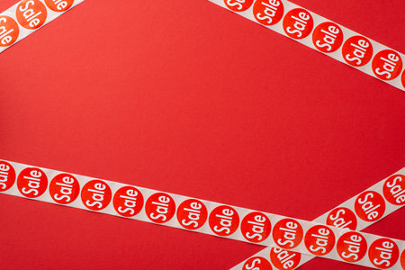 Frugal consumer Black Friday idea. Top view photograph showcasing sale stickers tape against a red...