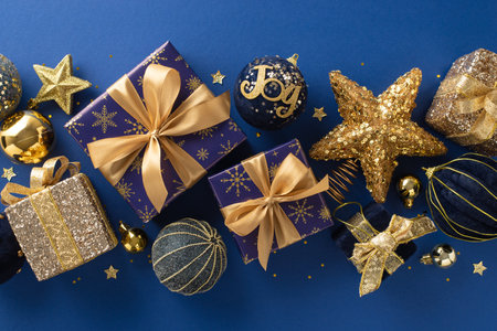 Lustrous Christmas Splendor: Top view picture of gleaming gold and blue-wrapped boxes, ornaments, star motifs, and tinsel on opulent sapphire surface ideal for your greeting or promotional textの写真素材