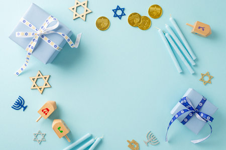Festival of Lights: Overhead image featuring Star of David, menorah signs, gelt, trendy gift boxes, candles and dreidel on a pastel blue background, circular space perfect for text or advertisingの写真素材
