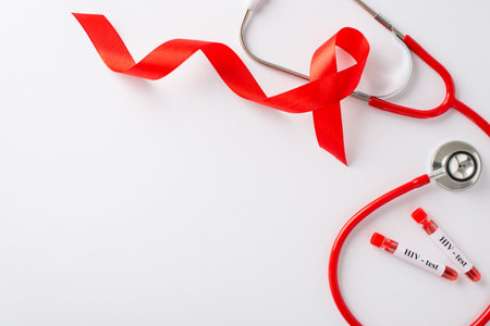 Illustration for AIDS Awareness Month: red ribbon, a doctor's stethoscope, and test tubes, all from a top view perspective on a white background with space for textの写真素材