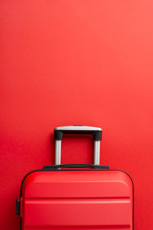 Festive adventure concept. Top view vertical photograph of trendy red suitcase on a red background, offering space for text or promotionの写真素材