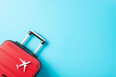 Ready for New Year's Getaway: Top view photograph of a red suitcase, and miniature plane against a bright blue background with advert spaceの写真素材