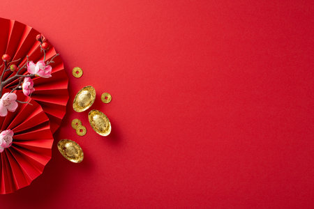 Embrace the Lunar New Year atmosphere: Top-view shot of fans, Feng Shui items, lucky coins, sycee and sakura on a red background, offering ample space for text or advertsの写真素材