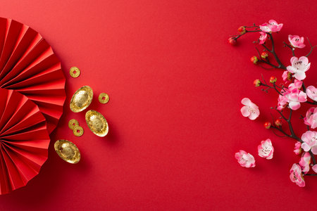 Celebrate prosperity with a top-view shot of Chinese New Year essentials: fans, Feng Shui items, lucky coins, sycee, and sakura on a vibrant red background. Ideal for text or adsの写真素材