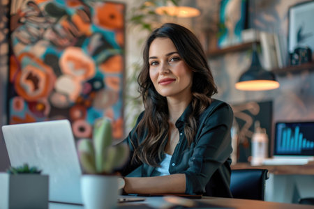 Confident young woman using a laptop in an artistic office environment filled with colorful artworks and modern decor, exemplifying a dynamic workspace. Generated A.I.の素材