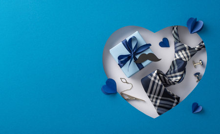 Show appreciation on Father's Day with a classy top view display of tie, cufflinks, giftbox and more against a blue background. Heart-shaped cutout adds a charming touchの写真素材