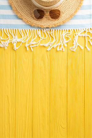 Tropical fantasy unveiled: vertical top view straw hat, sunglasses, beach blanket, on a sunny yellow surfaceの写真素材