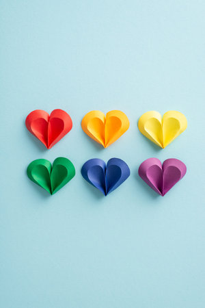 Celebrate diversity with a top view vertical photo of vibrant hearts on a pastel blue background,...