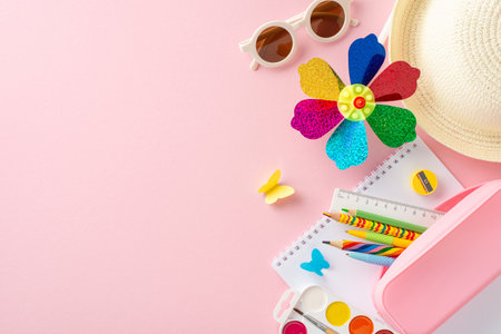Vibrant children's summer educational tools including a colorful pinwheel, school supplies, and a straw hat spread over a pink background, symbolizing fun learningの写真素材