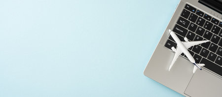 Top view of a laptop with a small airplane model on the keyboard, symbolizing travel booking and planningの写真素材