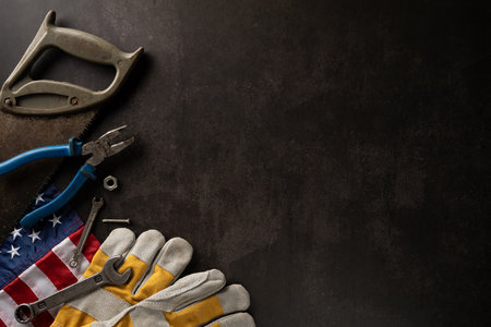 Flat lay of tools and American flag on dark background, representing Labor Day in the USA