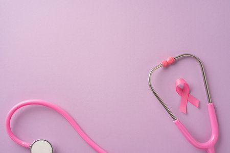 A symbolic image featuring a pink stethoscope alongside a pink ribbon on a light pastel background representing breast cancer awareness and health careの写真素材