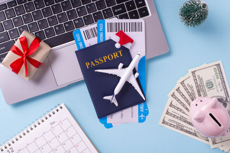 An overhead view of travel essentials including a passport, boarding passes, small airplane model, gift, and money, ideal for holiday travel planningの写真素材