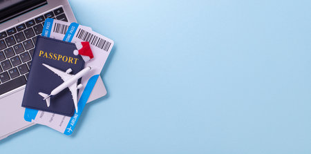 A passport, boarding pass, and toy plane on a laptop signifying travel preparation and holiday planningの写真素材