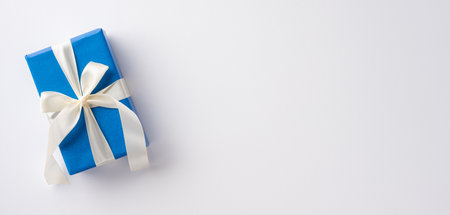 An elegant blue gift box wrapped with a white ribbon on a simple background, symbolizing celebration and giving. Perfect for Hanukkah or any festive occasionの写真素材