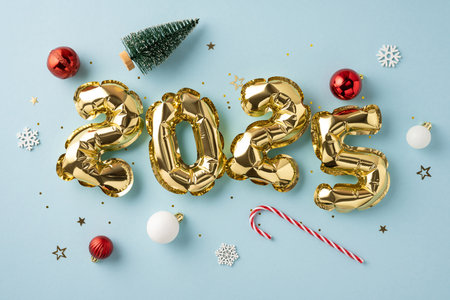 Celebratory scene featuring golden 2025 balloons surrounded by festive Christmas ornaments including candy canes, baubles, and snowflakes on a light blue backgroundの写真素材